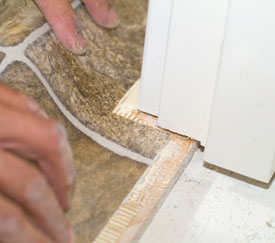 束乙烯基在门框和套管位置，以滑动前缘下。这可能需要几次尝试来修剪缺口，使地板平铺。