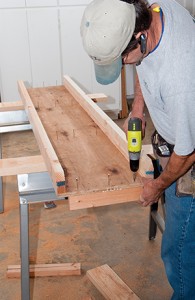 把桌子翻过来，用石膏板螺丝把翼板支撑块从桌子下面固定起来。