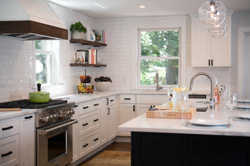 kitchen with white subway tiled walls and white stock cabinets that look custom