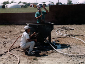 一个便携式混凝土搅拌机，一个混凝土泵，一个喷射混凝土枪，和软管都在演示中使用